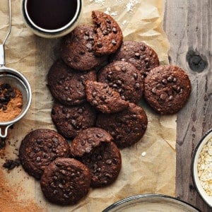 12 chocolate chips oats cookies placed on brown paper with black coffee on side.