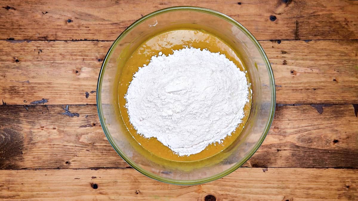 Dry ingredients flour mixture added into wet ingredients in bowl.
