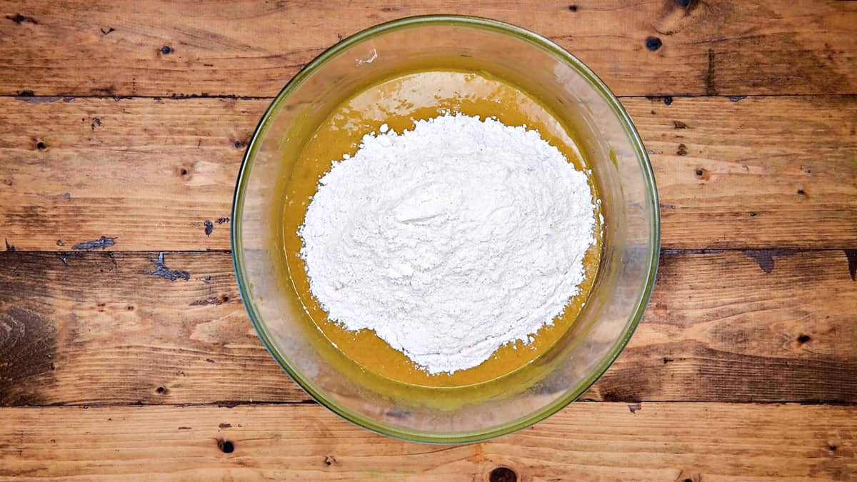 Dry ingredients flour mixture added into wet ingredients in bowl.