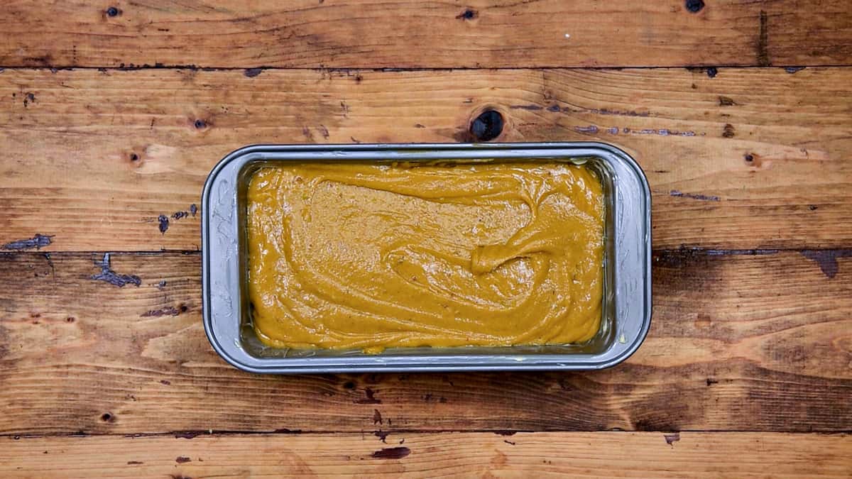 Pumpkin bread batter poured in greased and lined loaf pan.