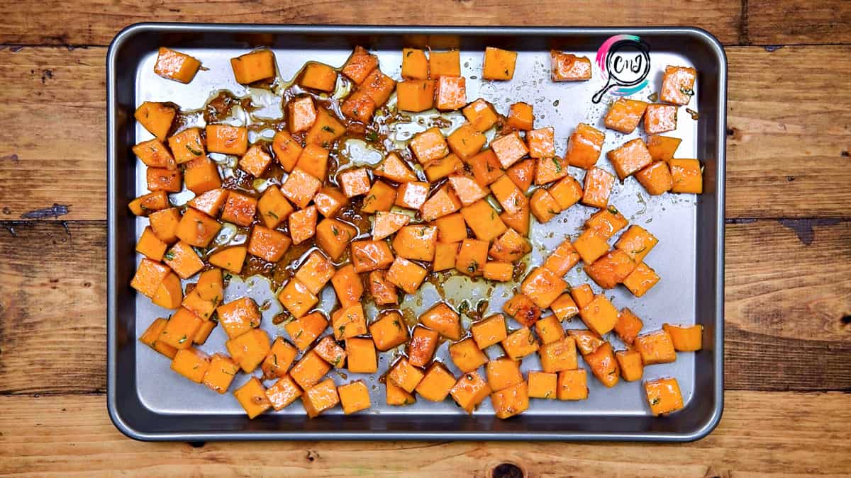 Tossed squash cubes placed on baking sheet in single layer.