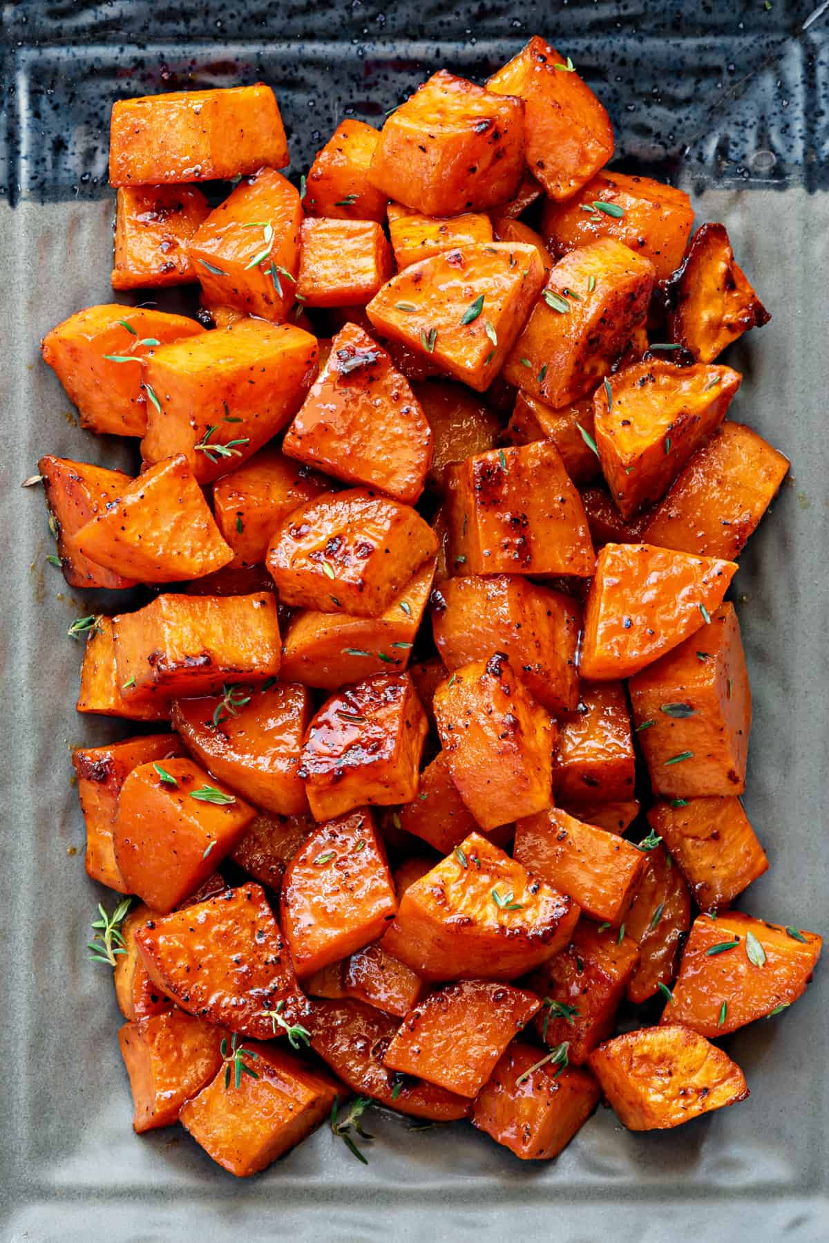 A shot from above, of a plate of roasted sweet potatoes with thyme. 