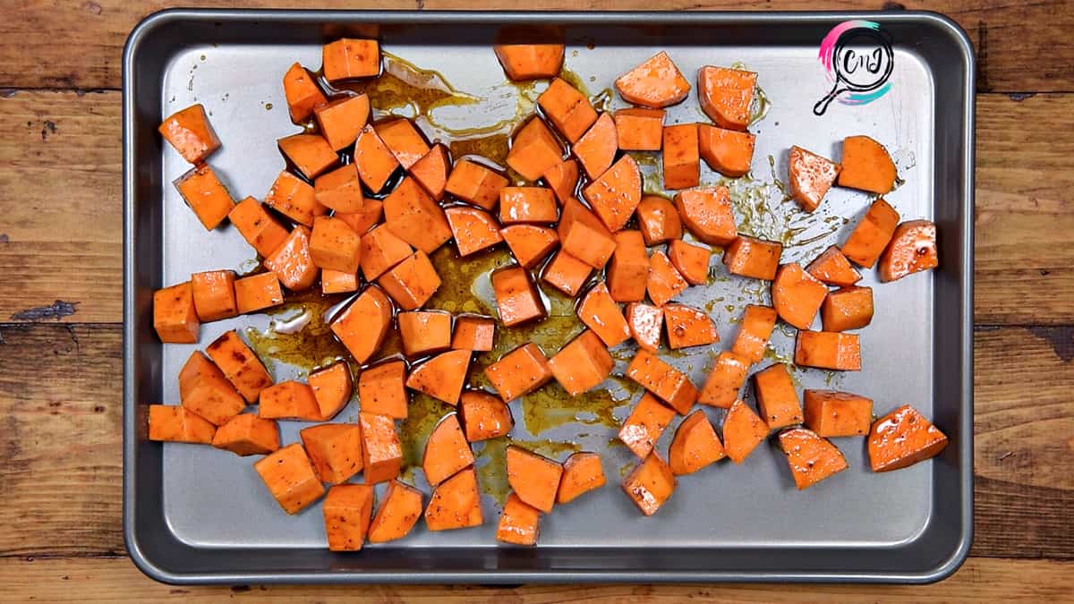 Tossed potatoes arranged in single layer on baking sheet pan.