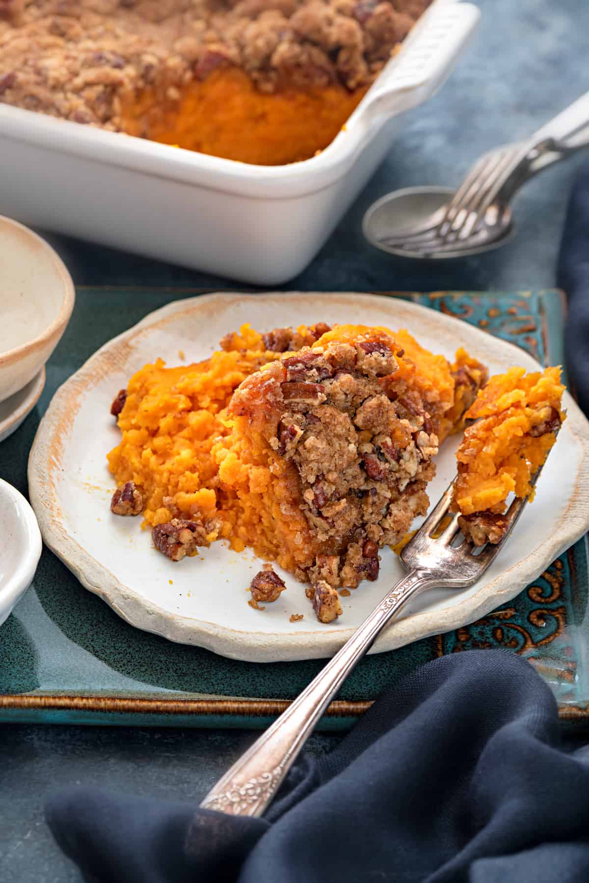 A small ceramic plate with a heaping scoop of sweet potato casserole and fork.  