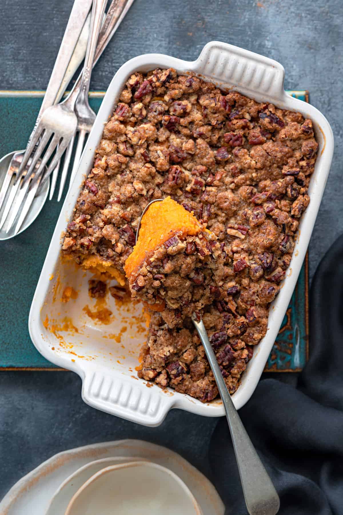 Overhead shot of a white casserole dish with scooped sweet potato casserole serving on spoon.