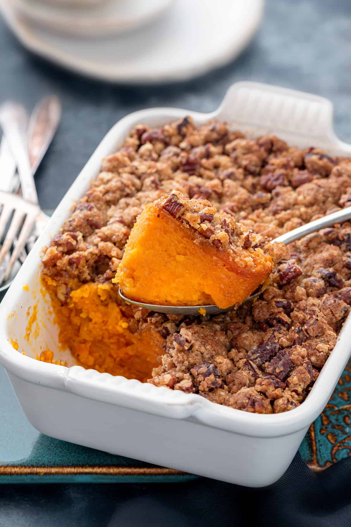 A casserole dish with a large scoop of sweet potato casserole taken out with the spoon.