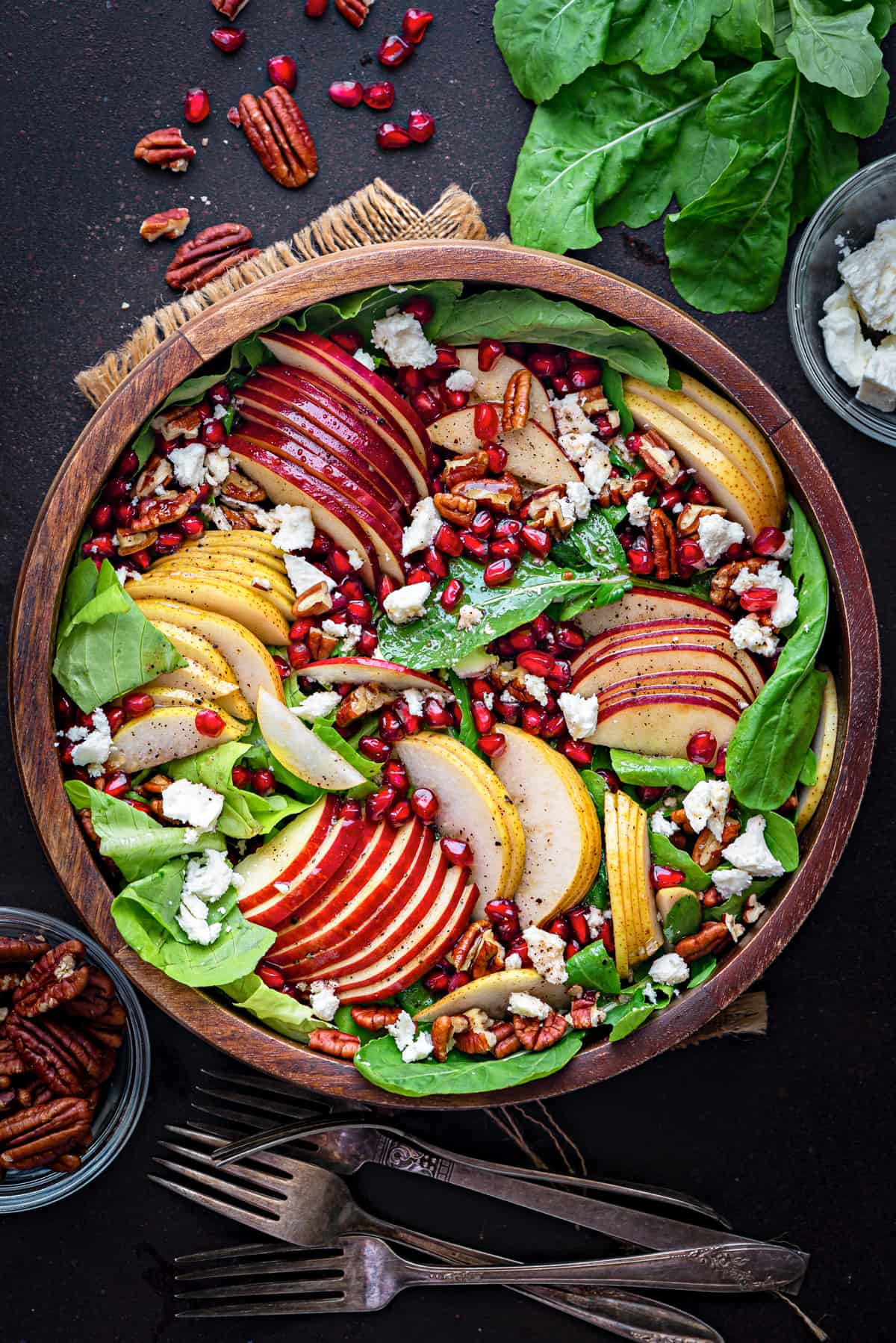 assembled autumn harvest fall salad in a wooden serving bowl with red apples slices, golden pears