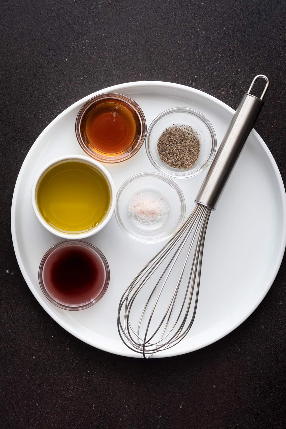 round white plate with small bowls holding maple vinaigrette mis en place and a silver whisk