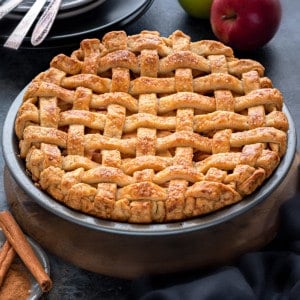 Close up shot of homemade apple pie with a crispy lattice crust placed in a dish.