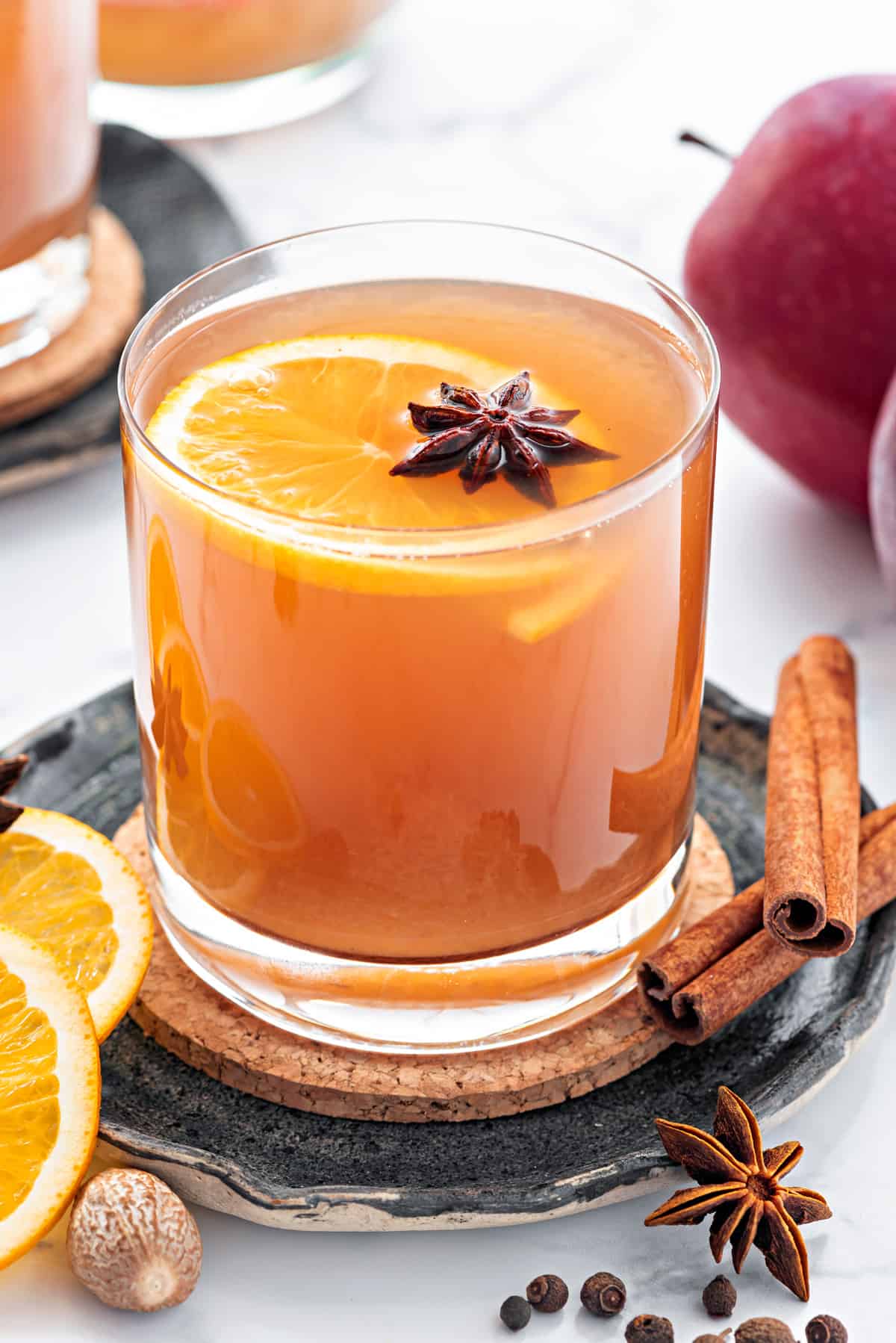 homemade apple cider in a glass with a slice of orange and star anise garnish