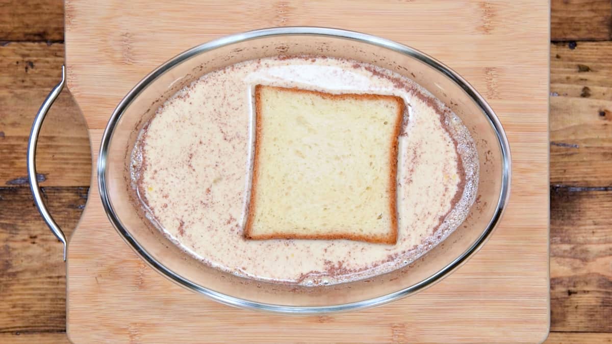 slice of brioche soaking in custard mixture for easy french toast recipe