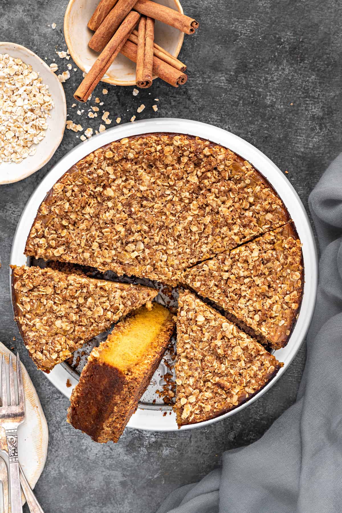 overhead shot of pumpkin cheesecake on a white serving platter with one slice turned on its side