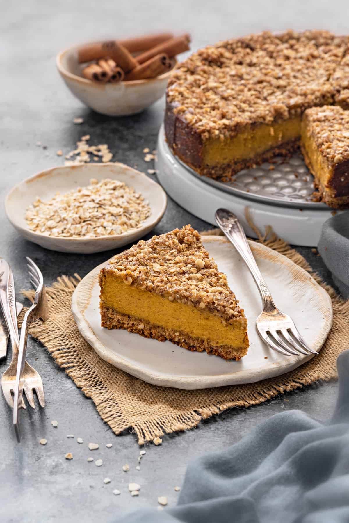slice of gluten free pumpkin cheesecake with oat crumble topping on a white plate with silver fork