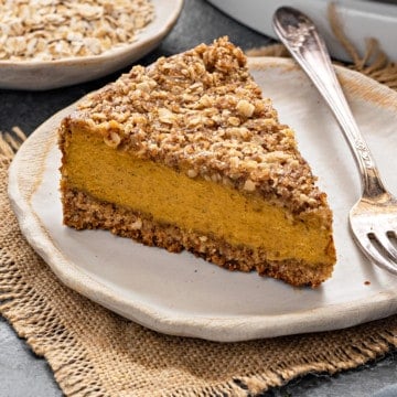 Close-up shot of pumpkin cheesecake slice placed with fork on white plate