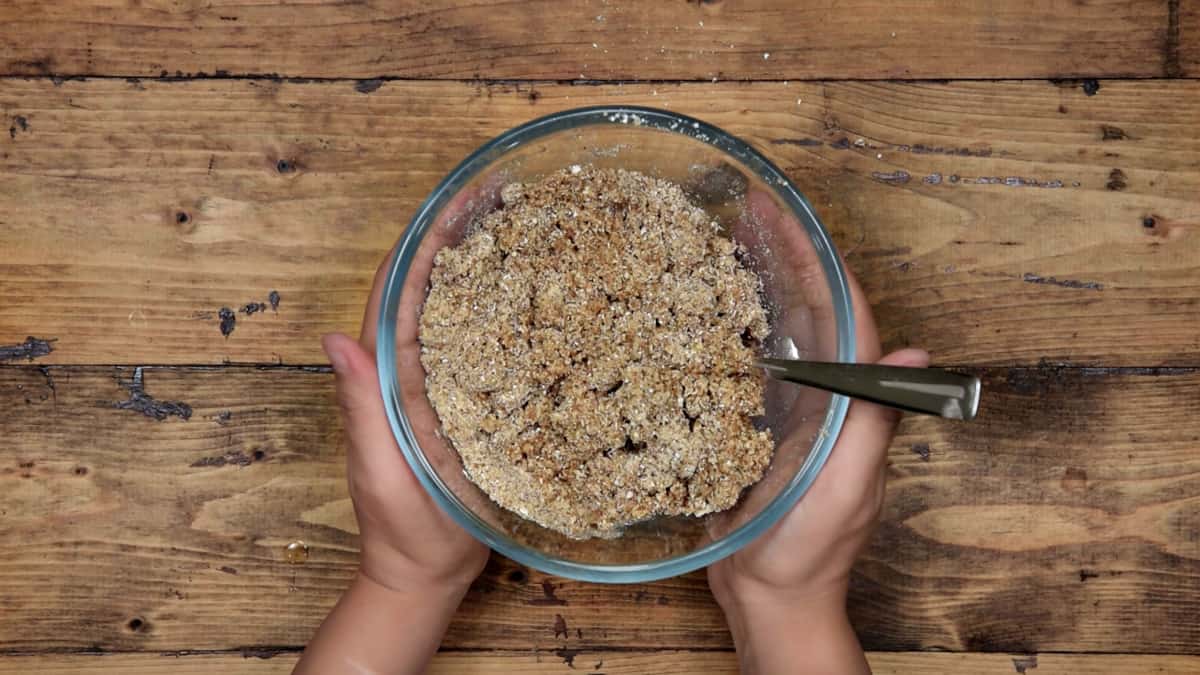 two hands holding a glass mixing bowl with gluten free crust mix