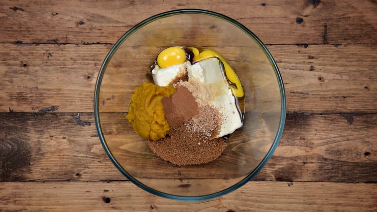 pumpkin cheesecake filling ingredients in a clear mixing bowl