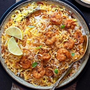 Closeup of Prawn biryani served in ceramic bowl with spoon into it.