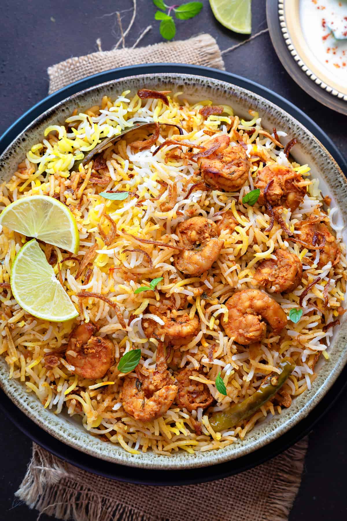 Closeup shot of prawn biryani served in grey ceramic bowl with a spoon placed into it.