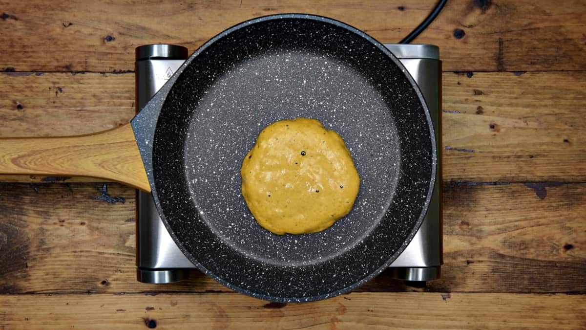pumpkin pancake cooking in a pan before being flipped