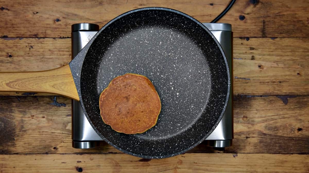 pumpkin spice pancake in a non-stick pan after being flipped