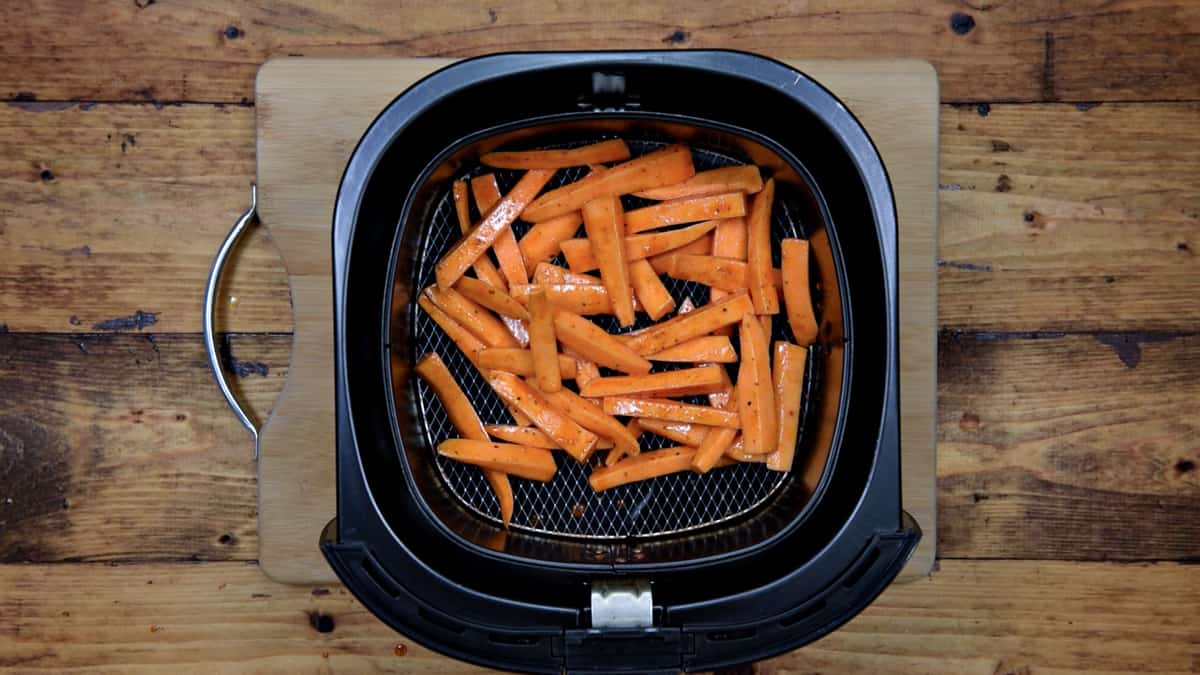 uncooked sweet potato fries in the basket of an air fryer