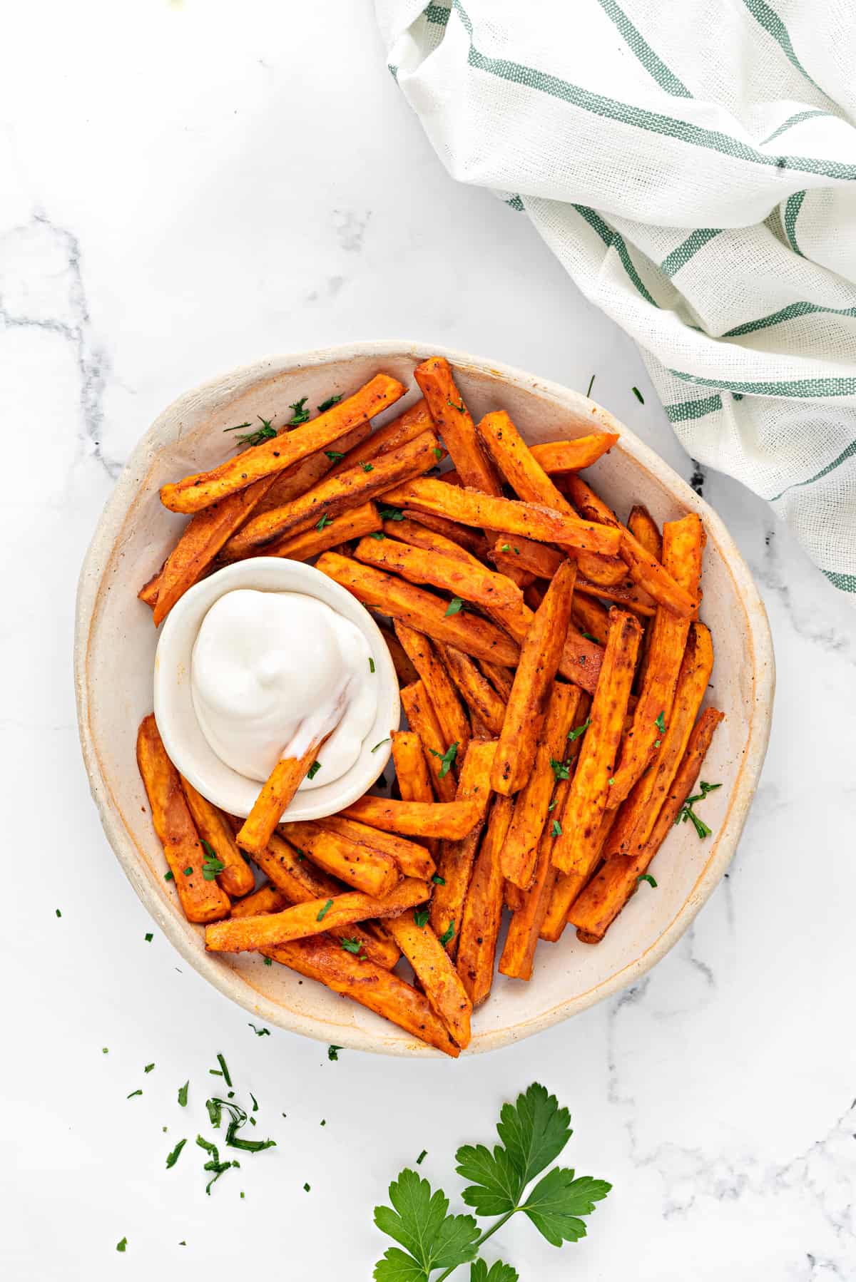 Oven baked sweet potato fries in a ceramic bowl with a small dipping bowl of aioli