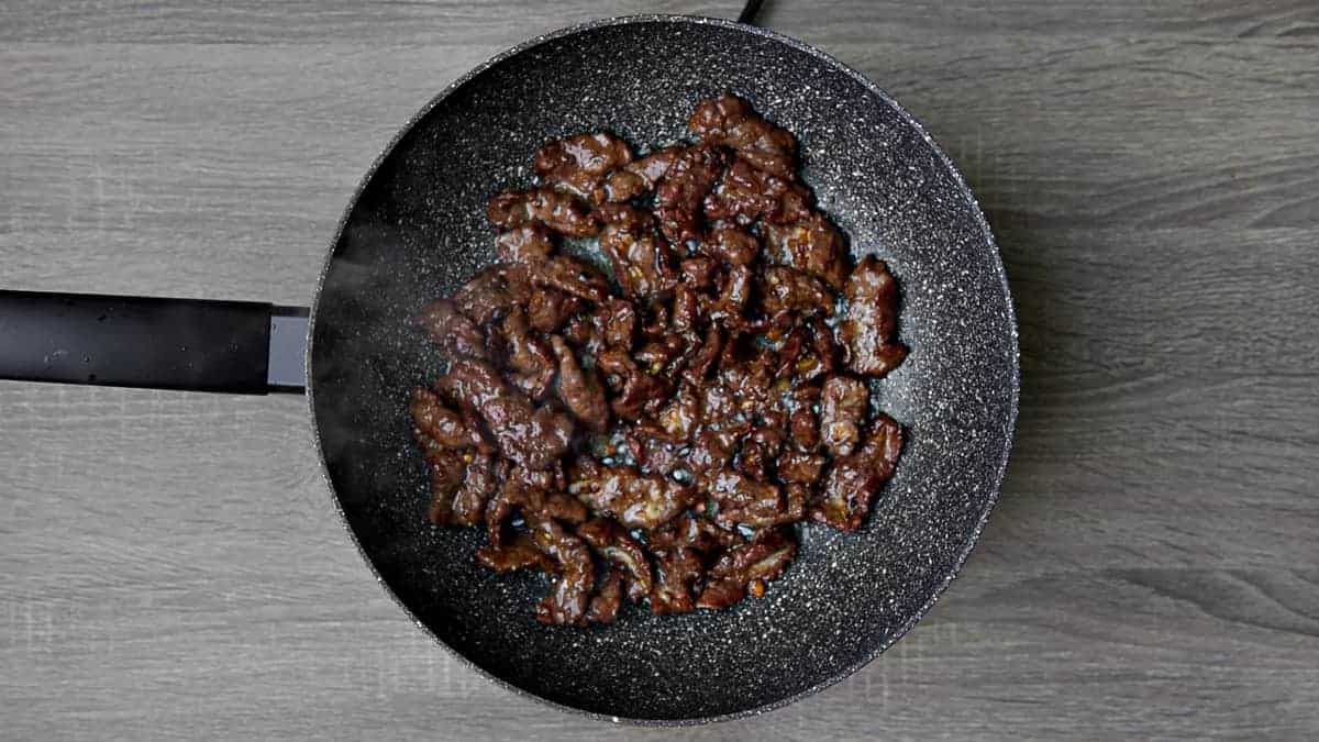 beef being stir fried in wok with ginger and garlic