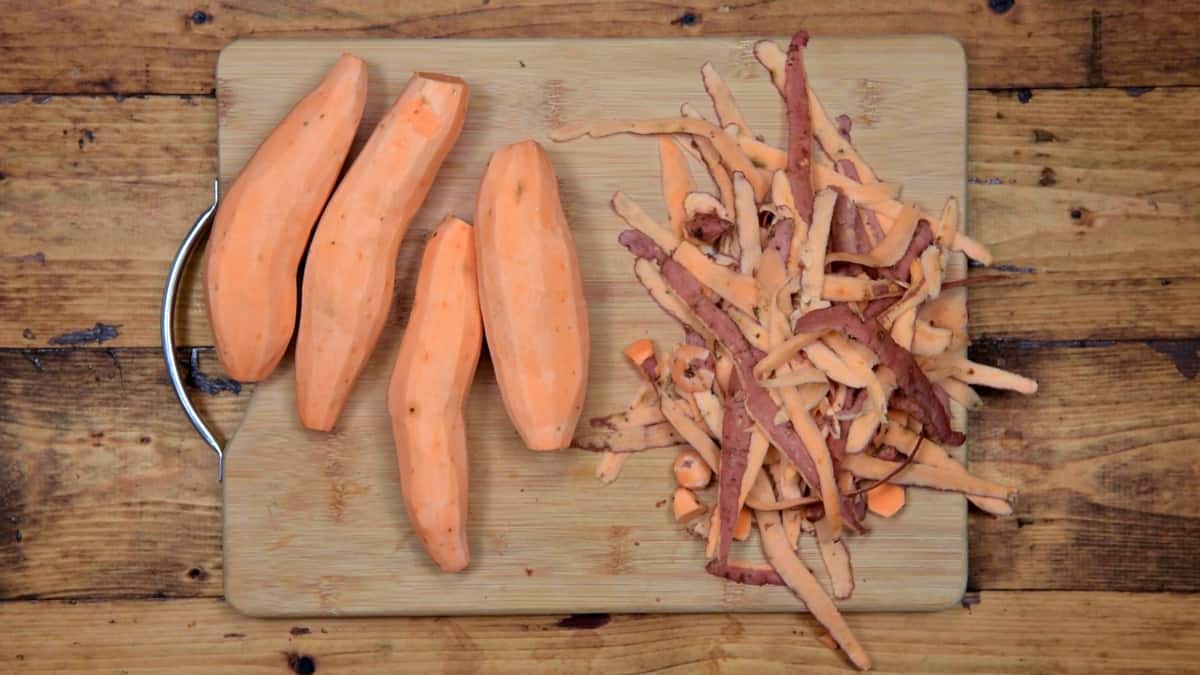 four sweet potatoes that have been peeled on a wooden cutting board
