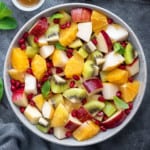 winter fruit salad garnished with fresh mint leaves in a white bowl