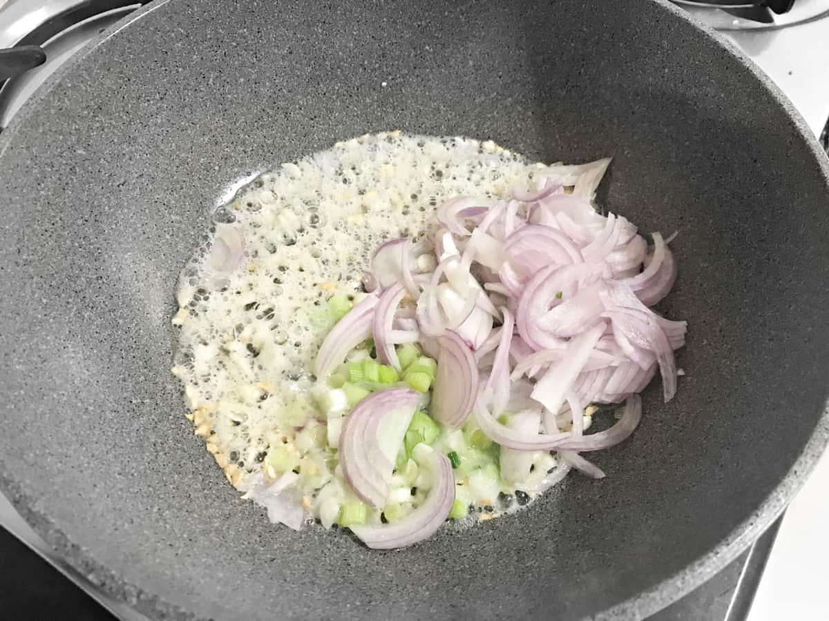 sliced red onions and spring onion whites added to wok with oil and garlic