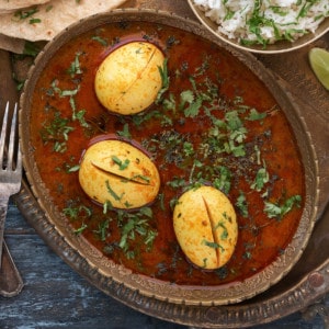 Egg curry placed in oval dish and served along with rice, chapathi side