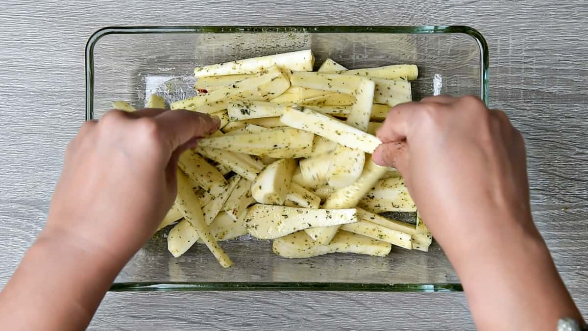 hands tossing parsnips to distribute oil and seasonings