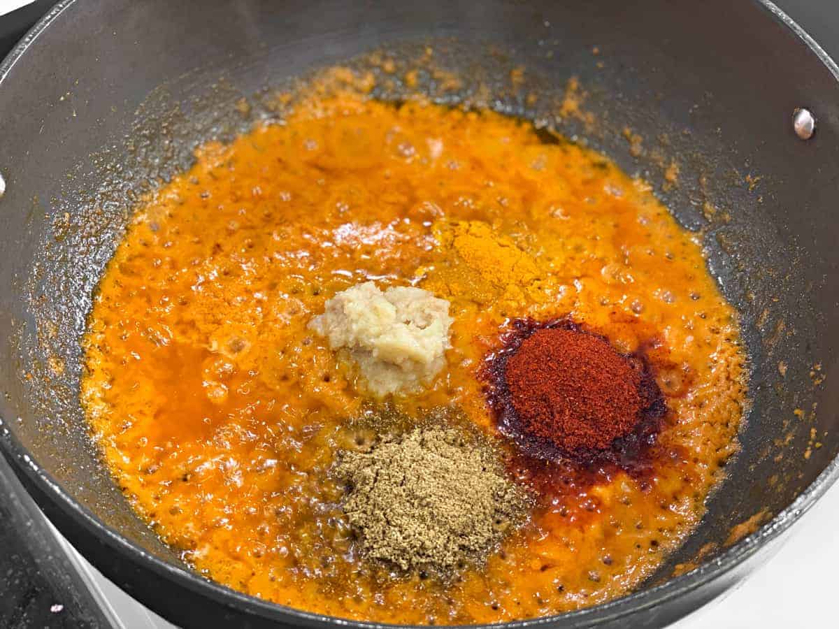 ginger garlic paste, turmeric, coriander and chili powder added to wok to make egg gravy for curry