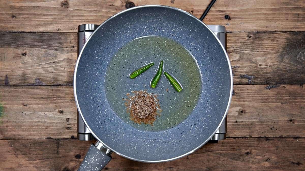 cumin seeds and slit green chilies added in hot oil in pan