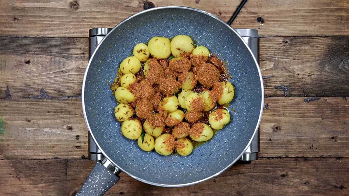 ground jeera masala added to the cooked potatoes in pan