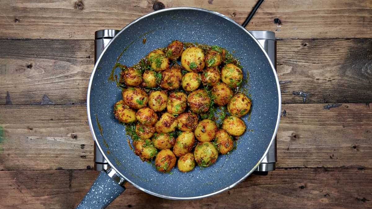 Cooked jeera aloo tossed with lime juice and fresh chopped cilantro in pan