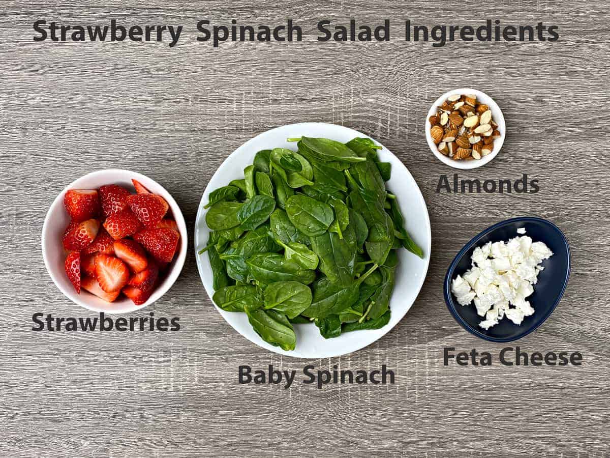 sliced strawberries, baby spinach, chopped almonds and feta cheese crumbles in bowls
