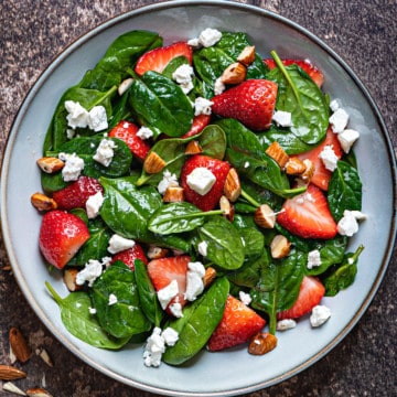 close up shot of strawberry spinach salad with feta cheese crumbles and chopped almonds