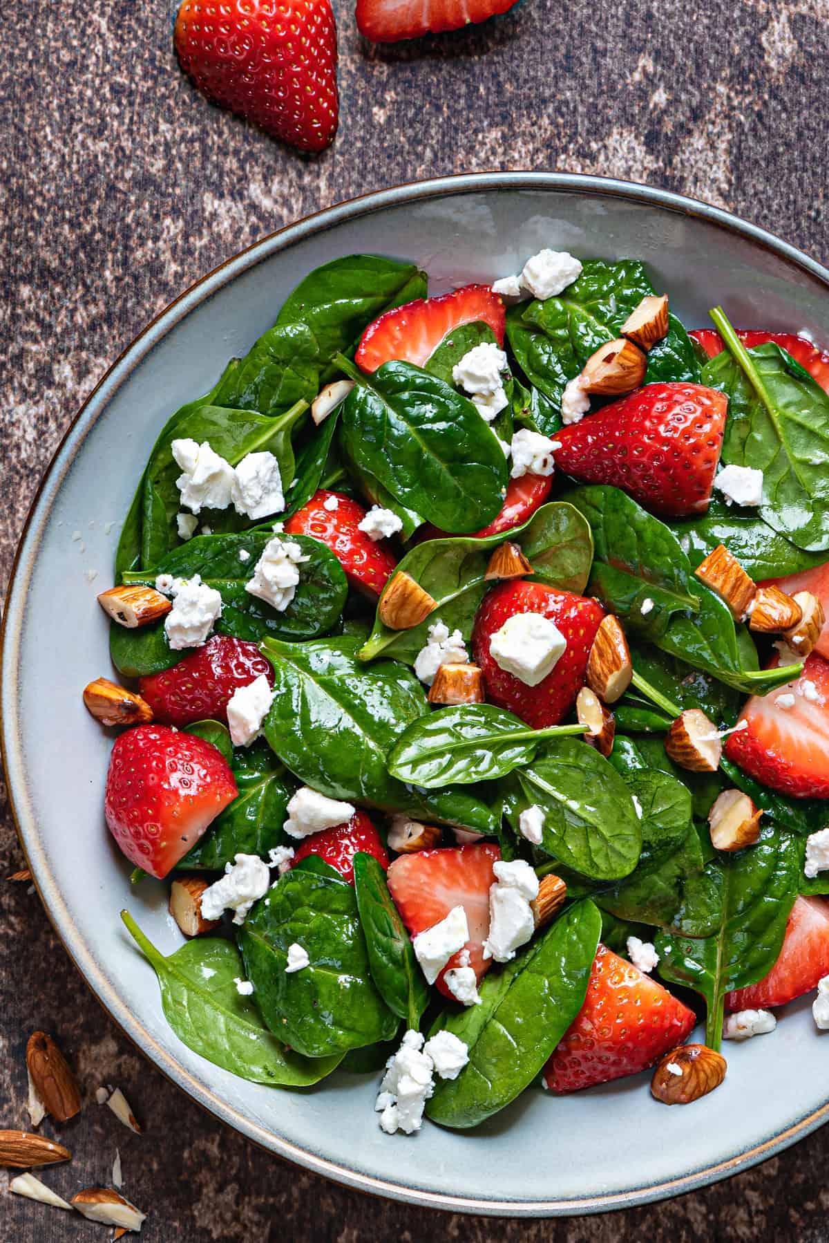 close up shot of strawberry spinach salad with feta cheese crumbles and chopped almonds