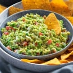 close up shot of homemade guacamole dip and yellow tortilla chips