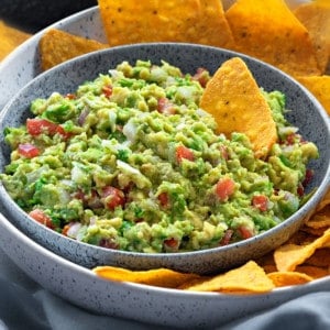 close up shot of homemade guacamole dip and yellow tortilla chips