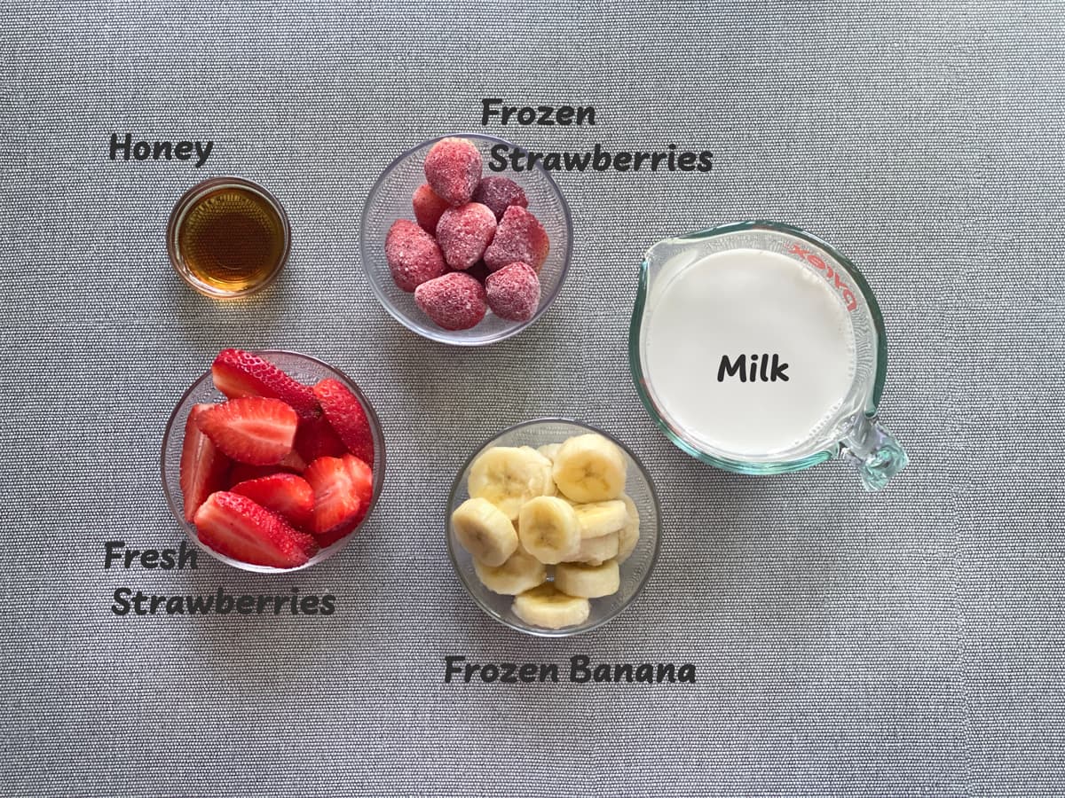 ingredients for banana strawberry smoothie recipe laid out on a grey table
