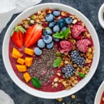 Frozen fruits and mixed berry smoothie bowl topped with fruits, chia seeds and muesli