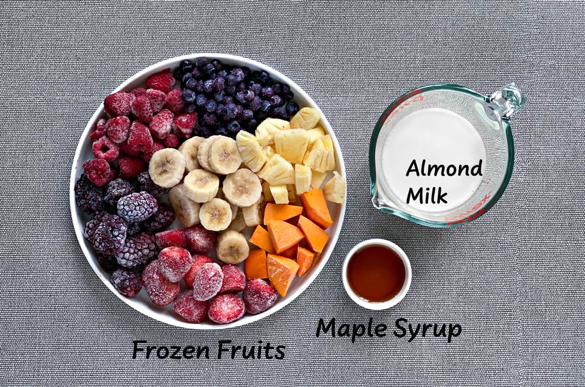 ingredients for frozen fruit smoothie bowls laid out on a grey tabletop