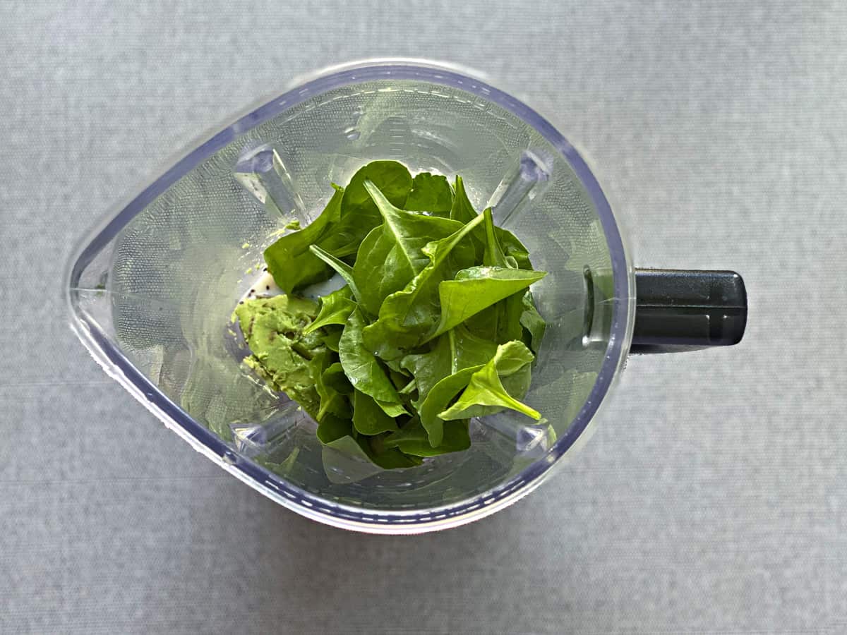 avocado breakfast smoothie ingredients in the base of a blender before blending