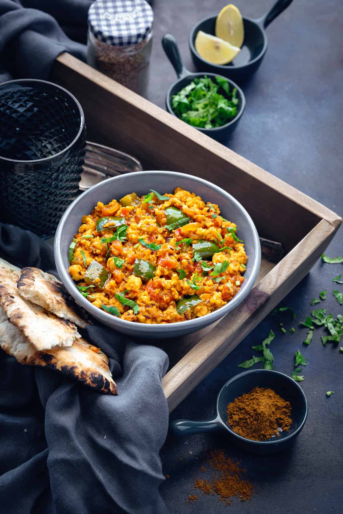 Paneer Bhujia serving in a ceramic bowl placed on wooden tray with bread