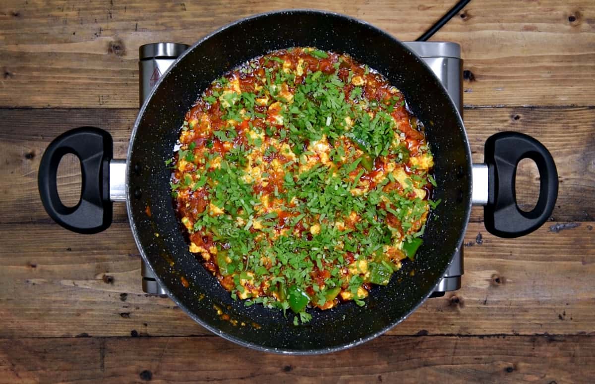 Finished paneer bhurji in pan topped with squeezed lemon and chopped cilantro