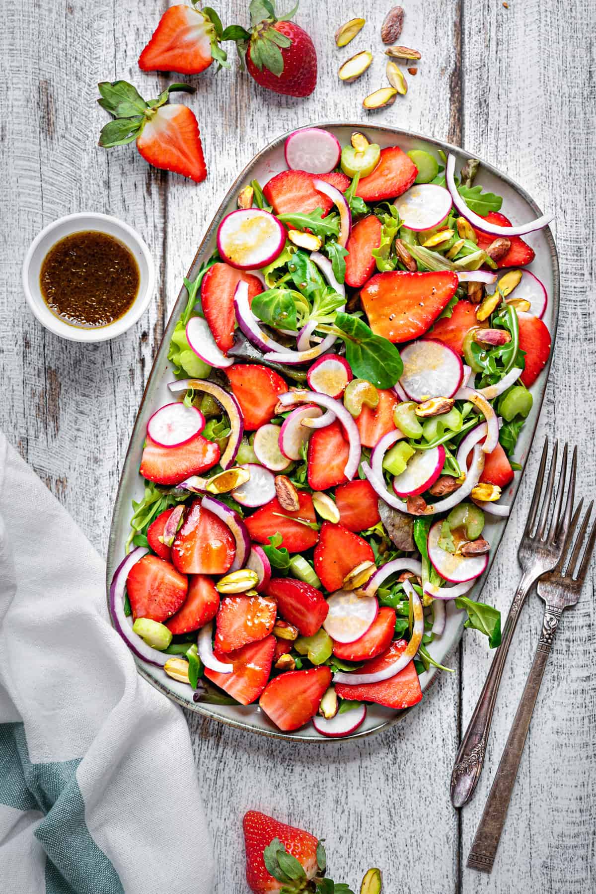 overhead shot of summer strawberry salad on a rectangular serving tray on a white wooden table