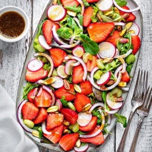 overhead shot of summer strawberry salad on a rectangular serving tray on a white wooden table