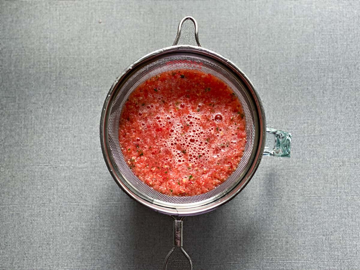fruit juice being strained into a pitcher after blending